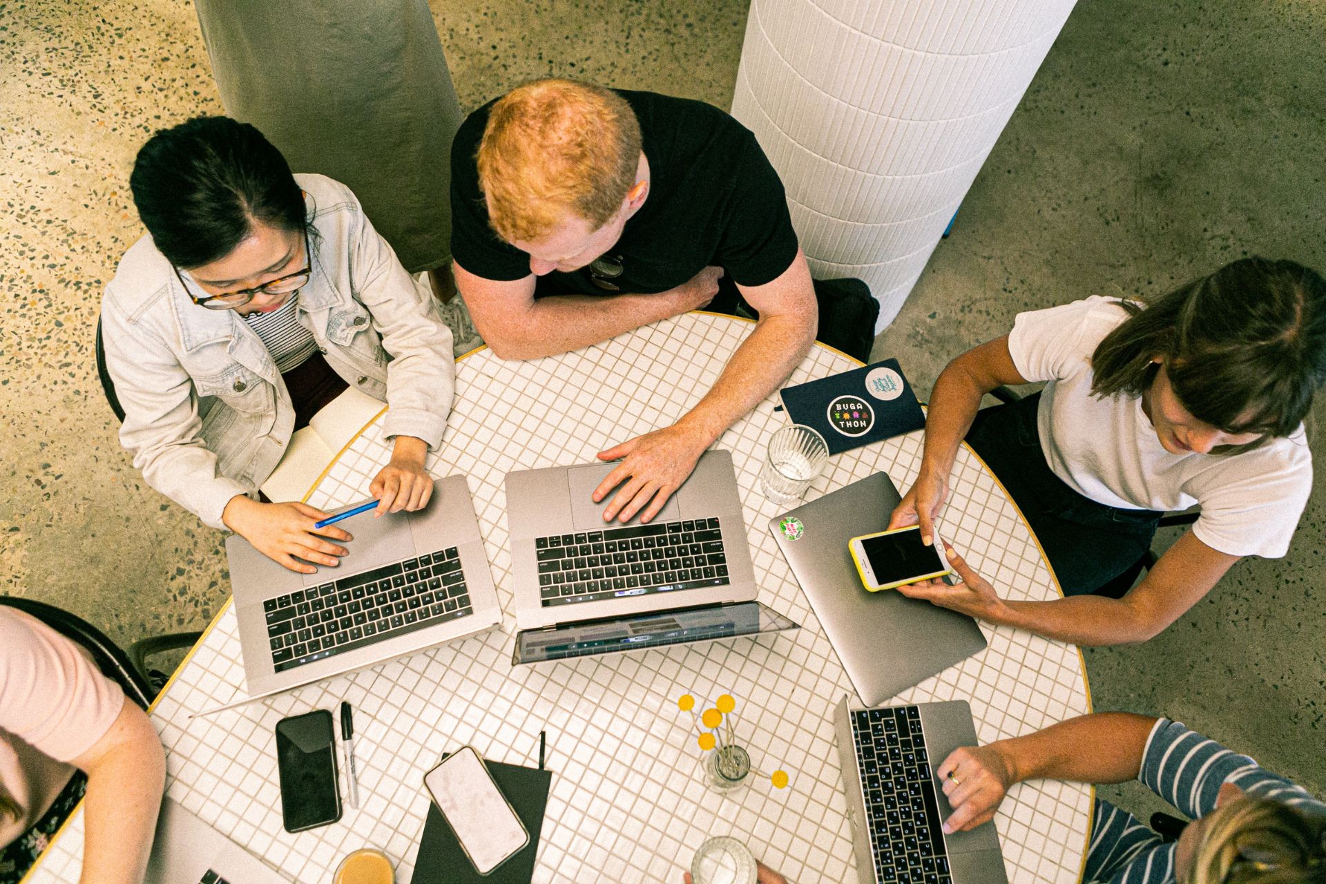 Large team crowded around a desk in a small shared office