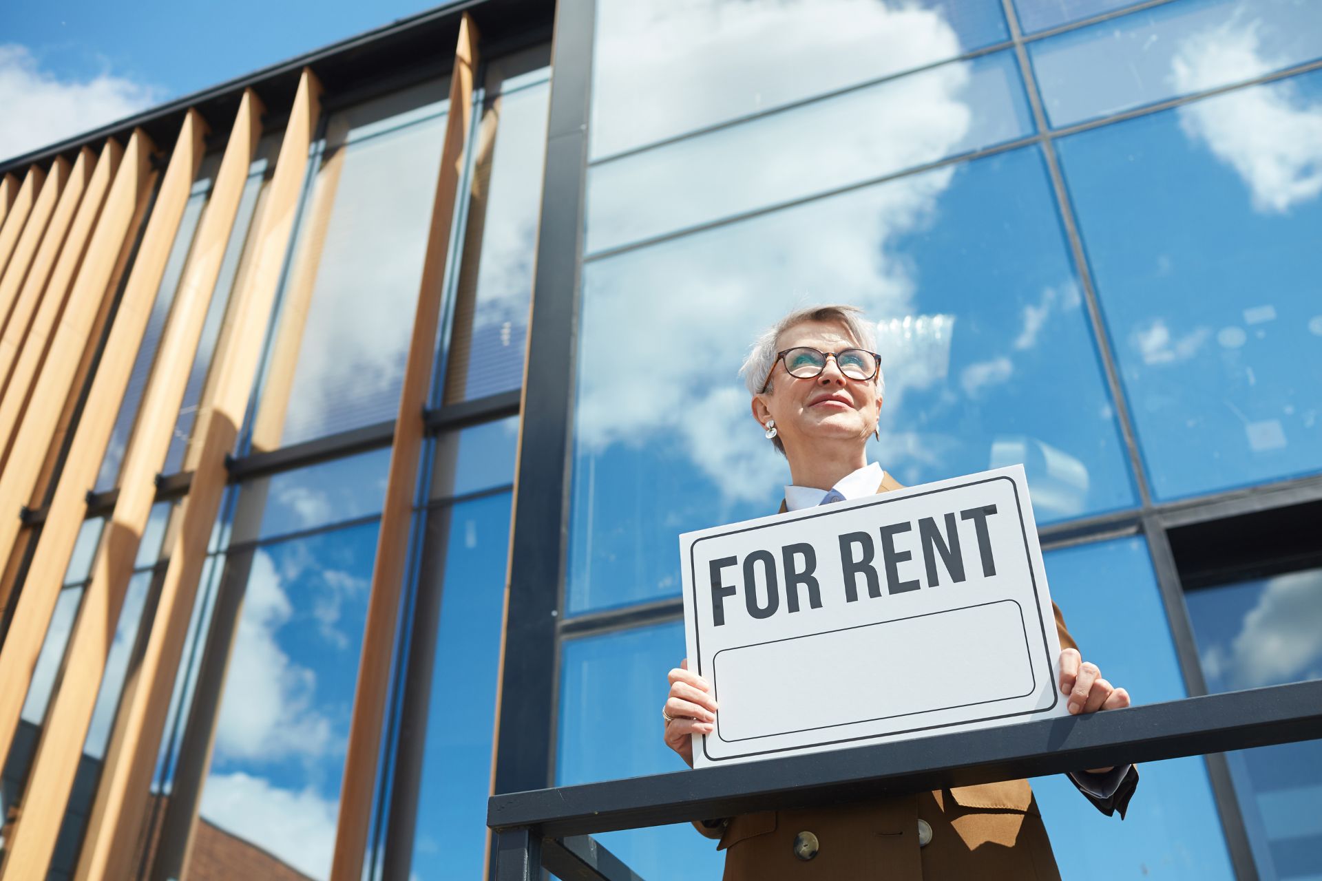 a real estate agent holds a For Rent placard