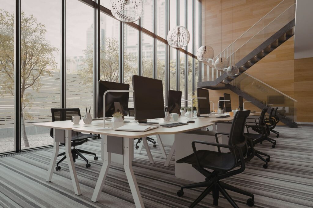 tall office with shared desk, office chairs and big windows.