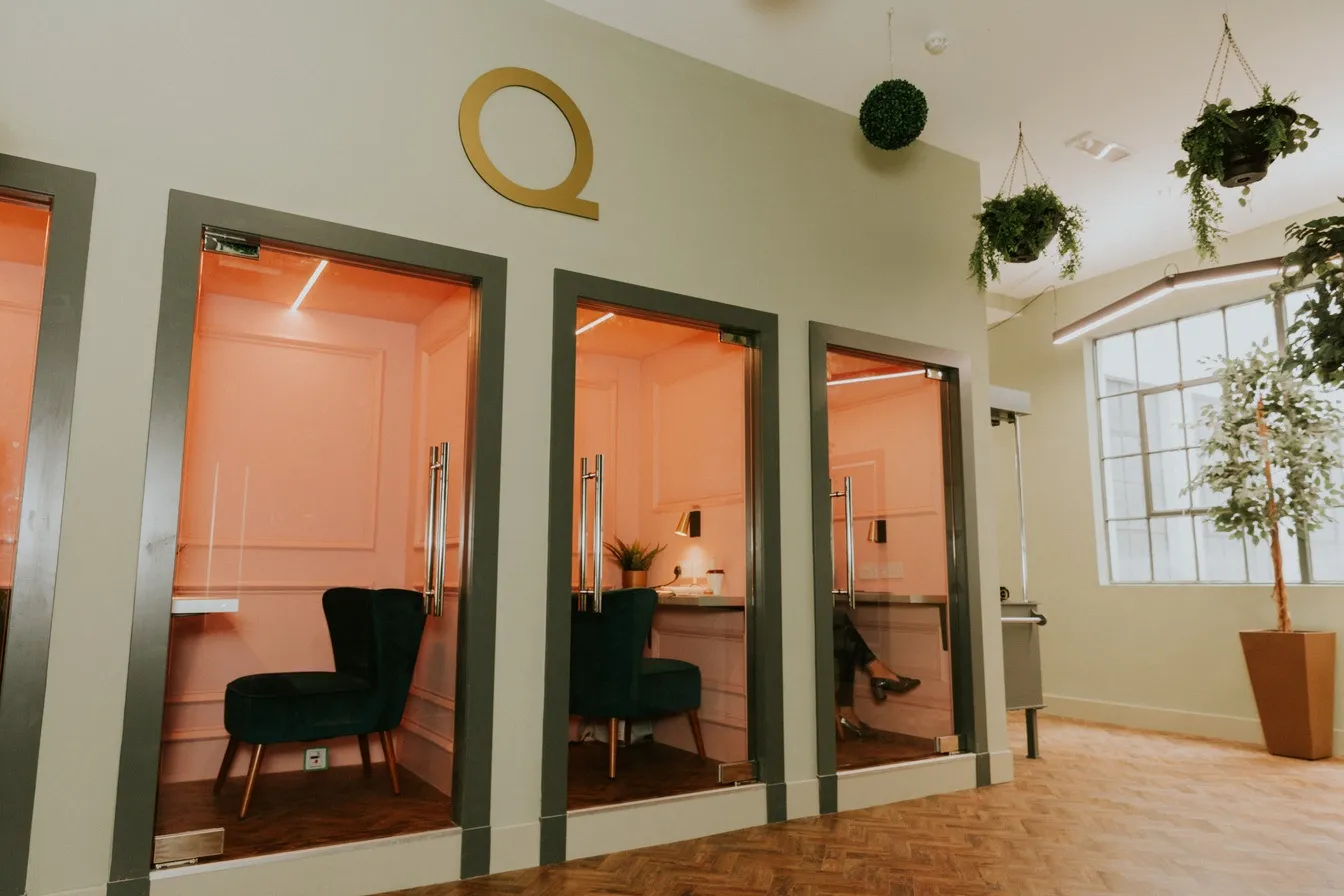 Acoustic booths with green armchairs beneath the gold Q at Kollaborate House