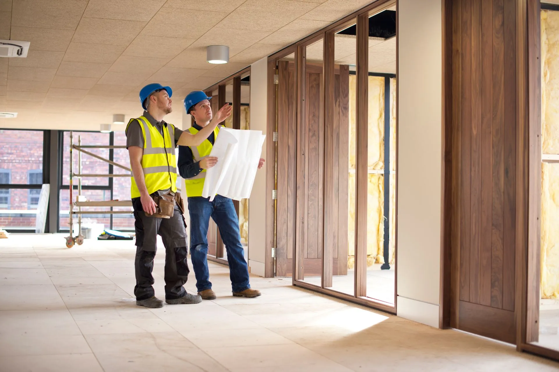 Two contractors in hi-vis reviewing plans during an office fit-out