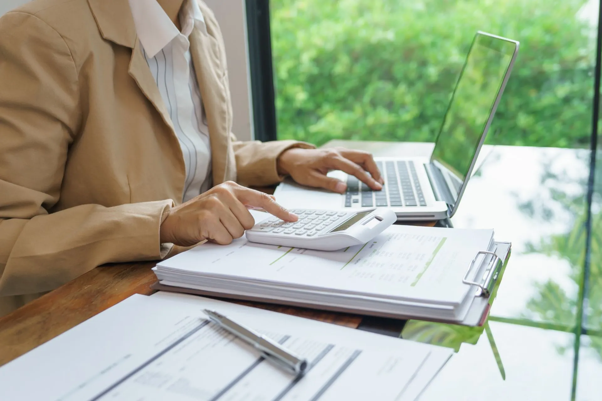 Person using a laptop and calculator to review insurance paperwork