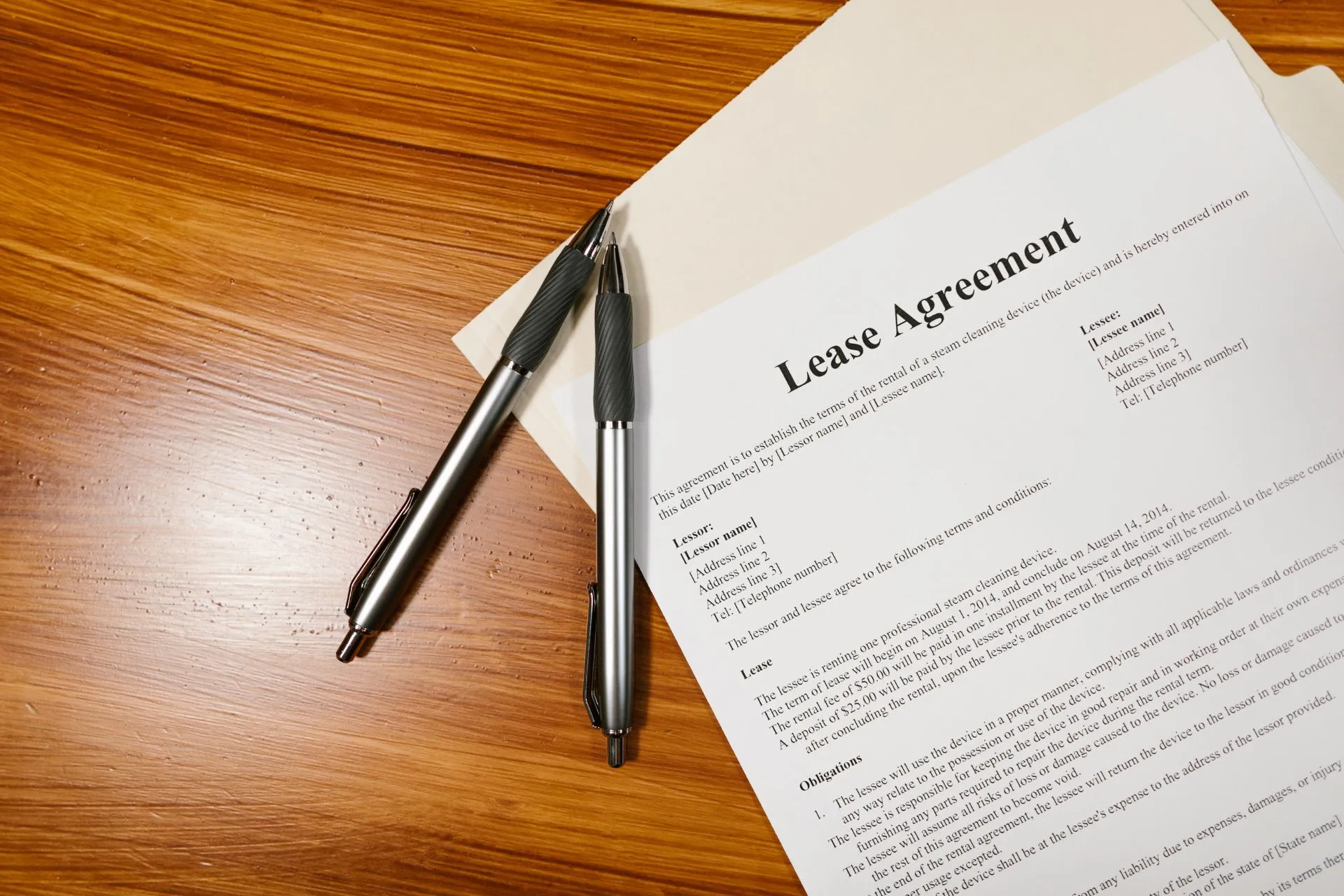 Lease agreement document and two pens on a wooden desk
