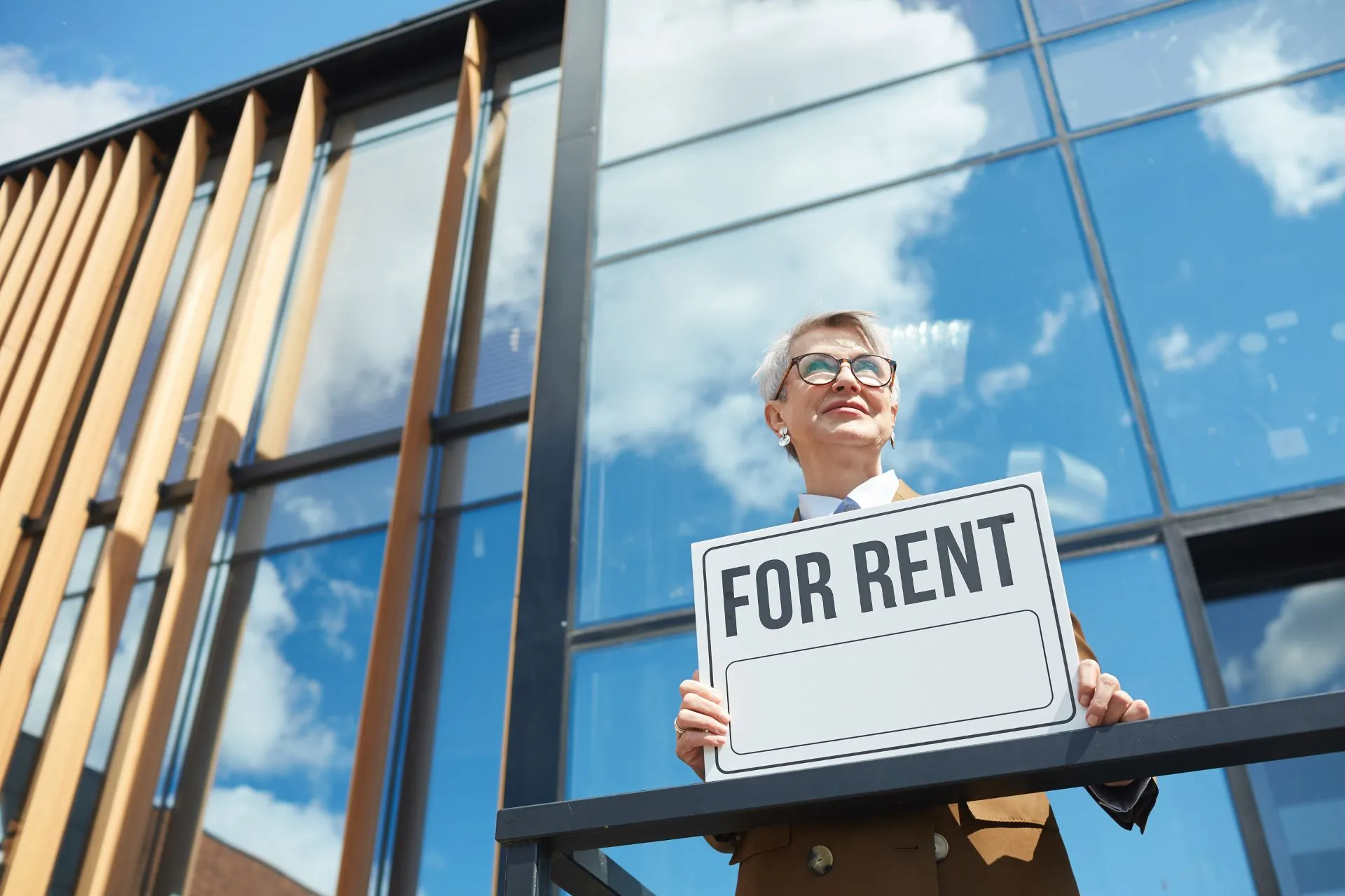 a real estate agent holds a For Rent placard