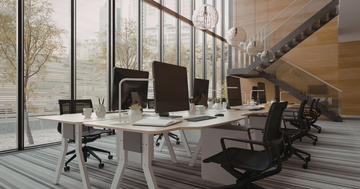 tall office with shared desk, office chairs and big windows.